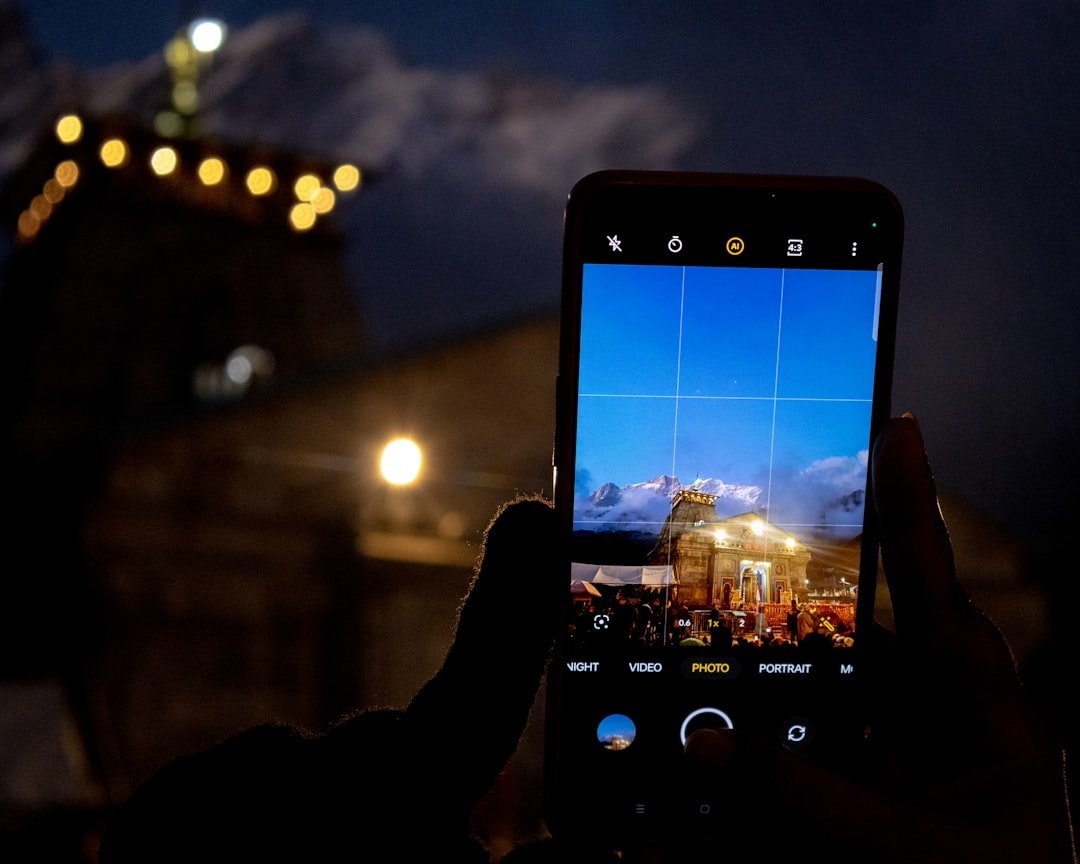 Smartphone displaying aurora forecast app with northern lights in background sky